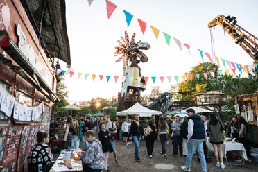 Odonien Ein lebhafter Markt mit bunten Wimpeln, fröhlichen Menschen und kreativen Skulpturen.