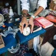 Odonien A person holds an old alarm clock above a flea market stall with various everyday objects.