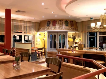 Ein einladendes Restaurant mit hellen Holztischen, bequemen Stühlen und einer stilvollen Bar.