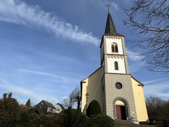 ev. Bartholomäuskirche <p>Gelbe Kirche mit Glockenturm in Lohmar vor blauem Himmel und umliegender Natur.</p>