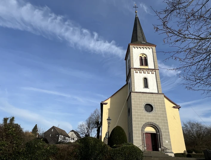 ev. Bartholomäuskirche <p>Gelbe Kirche mit Glockenturm in Lohmar vor blauem Himmel und umliegender Natur.</p>