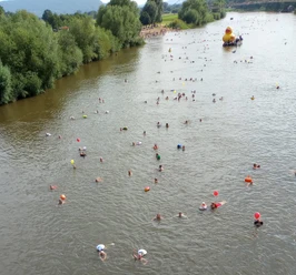 Weserschwimmen DLRG 2023.jpg Schwimmer mit bunten Badekappen im Fluss, im Hintergrund eine riesige gelbe Badeente.