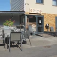 PS Cafe_4448.jpg Ein Café mit Kaffee-Wandgemälde, Außenterrasse und Tischen. Zugang über flache Rampe möglich.