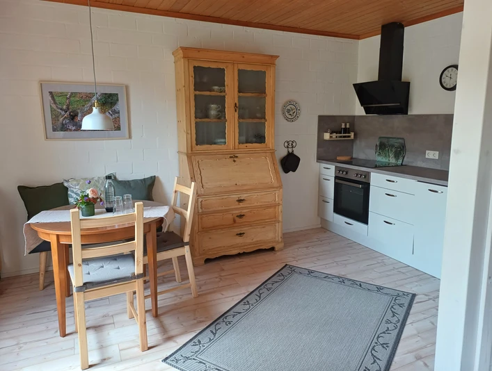 FeWo am Bärenkamp Küche/Essbereich.jpg Küche und Essbereich mit Holzmöbeln, Esstisch, weißer Küchenzeile und dekorativen Elementen.