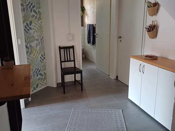 Großzügiger Eingangsbereich mit hellen Wänden, modernem Teppich und dekorativer Holzbalkendecke.