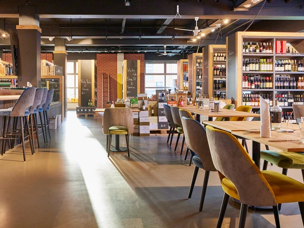 Kornbrennerei Sonnenschein, Witten Gemütlicher Innenraum einer modernen Weinbar mit stilvollen Sitzmöglichkeiten und Regalen voller Weinflaschen.