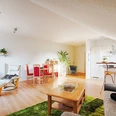 FeWo Herbert Wohnbereich 2.jpg Moderner Wohnbereich in Ferienwohnung mit hellen Möbeln, offener Küche, Essbereich und Pflanzen.