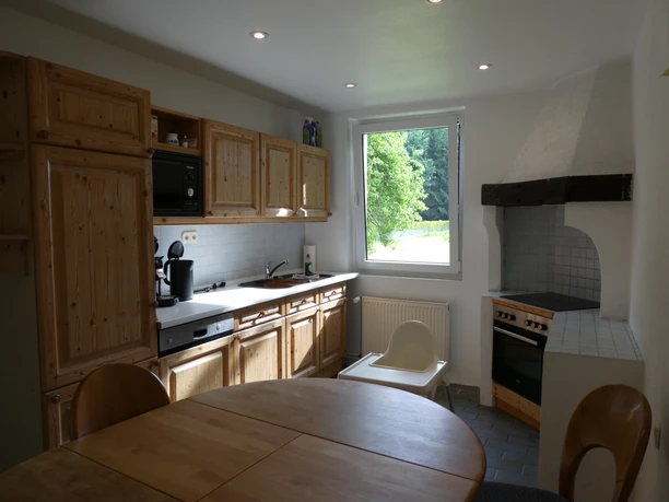 Ferienwohnung "Urlaub in Belle" Küche.jpg Helle, geräumige Küche mit Holzmöbeln, offenen Regalen, modernem Gerät und Fensterblick ins Grüne.