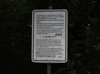 Gedenktafel mit historischem Text zu König Wilhelm I. von Hannover, umgeben von dichter Waldvegetation.