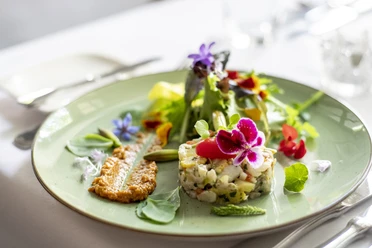 Fine Food Days Cologne Gehobene Küche, ein Teller mit schön angerichteten und mit Blumen dekorierten Speisen.