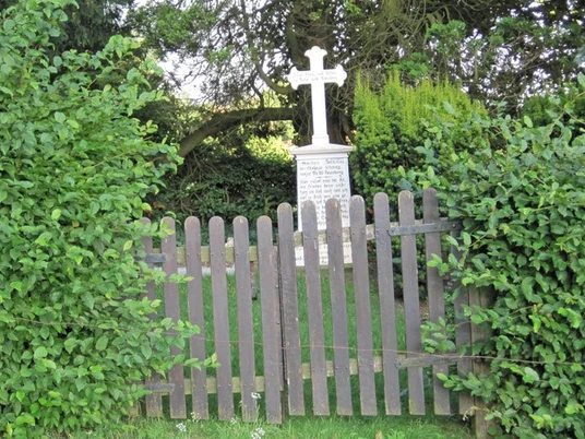 ahlsen-reineberg-privatfriedhof-01.jpg Ein kleiner, von grünen Büschen umgebener Friedhof mit einem Holzzaun und einem weißen Kreuzgrabstein.