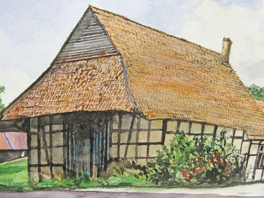 ahlsen-reineberg-heuerlingshaus-01.jpg Heuerlingshaus aus Fachwerk mit Reetdach in ländlicher Umgebung, umgeben von grüner Vegetation.