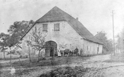 ahlsen-reineberg-domaenenschaeferei-01.jpg Ein altes, zweistöckiges Gebäude mit Satteldach, umgeben von Bäumen und einer unbefestigten Straße.