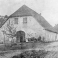 ahlsen-reineberg-domaenenschaeferei-01.jpg Ein altes, zweistöckiges Gebäude mit Satteldach, umgeben von Bäumen und einer unbefestigten Straße.