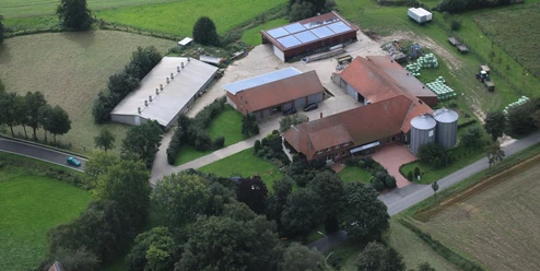 broederhausen-hof-bloebaum-aktuell.JPG Luftaufnahme eines bäuerlichen Hofes mit Scheunen, Silos, Solardach und umgeben von grünen Feldern.