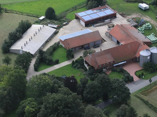 broederhausen-hof-bloebaum-aktuell.JPG Luftaufnahme eines bäuerlichen Hofes mit Scheunen, Silos, Solardach und umgeben von grünen Feldern.