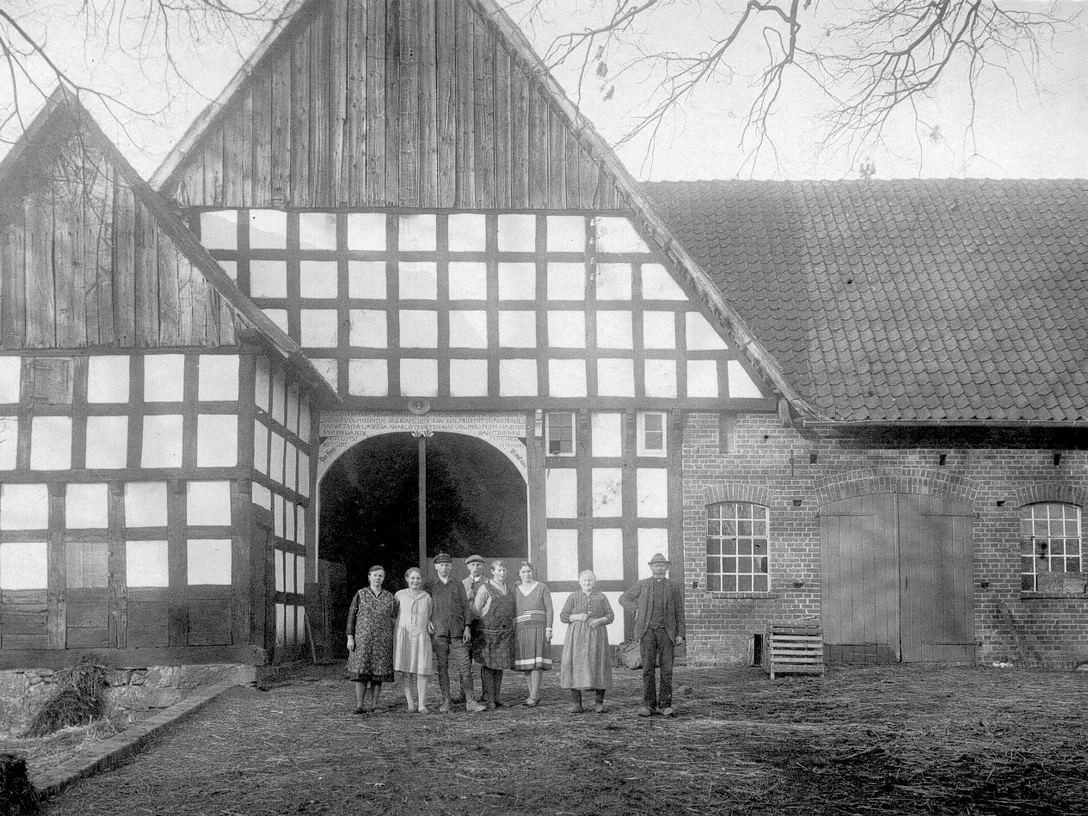broederhausen-feuerwehrgeraetehaus.jpg Historisches Fachwerkgebäude mit Menschen in traditioneller Kleidung davor, aufgenommen in Broderhausen.