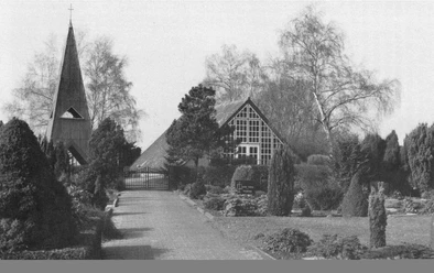 buettendorf-friedhofskapelle -frueher.jpg Die Friedhofskapelle Büttendorf steht umgeben von Bäumen und grünen Sträuchern neben einem Kirchweg.
