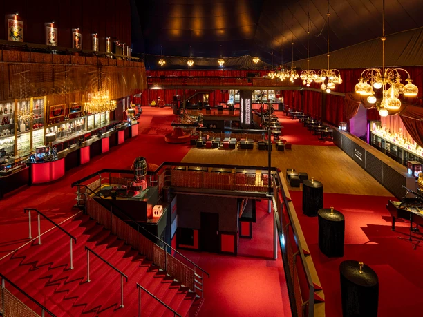04_MDK_Foyer1 großes Foyer mit mehreren Bars, Kronleuchtern und Sitzgelegenheiten, Boden und Vorhänge in rot
