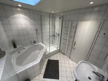 Modernes Badezimmer mit Eckbadewanne, Dusche und Waschbecken, hell gefliest, mit Oberlicht.