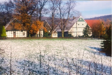 holsen.jpg Fachwerkhäuser in einer ländlichen Landschaft mit Bäumen und teils schneebedeckten Wiesen im Vordergrund.