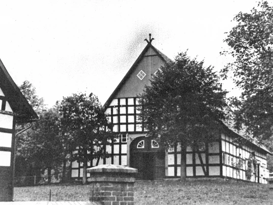 holsen-hof-sielermann.jpg Historischer Fachwerkhof, umgeben von Bäumen, mit Satteldach und mehreren großen Fenstern, ländlich gelegen.