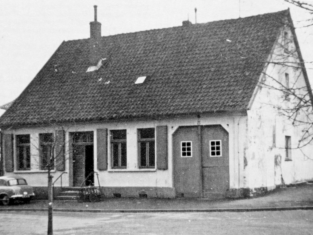 huellhorst-rathaus-alt.jpg Historisches Rathaus in Hüllhorst mit einem Satteldach, alten Fenstern und einem davor geparkten Oldtimer.