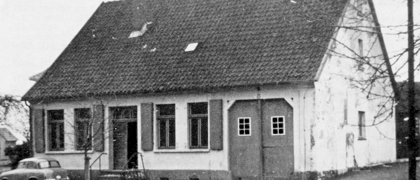 huellhorst-rathaus-alt.jpg Historisches Rathaus in Hüllhorst mit einem Satteldach, alten Fenstern und einem davor geparkten Oldtimer.