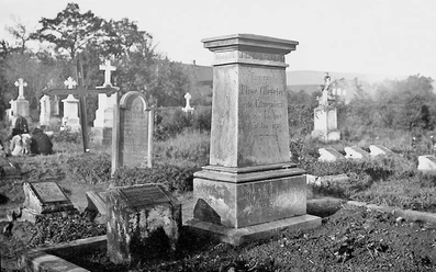huellhorst-alter-friedhof.jpg Alter Friedhof mit verwitterten Grabsteinen und einem dominanten zentralen Monument, umgeben von Bäumen.