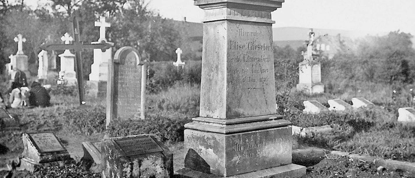 huellhorst-alter-friedhof.jpg Alter Friedhof mit verwitterten Grabsteinen und einem dominanten zentralen Monument, umgeben von Bäumen.