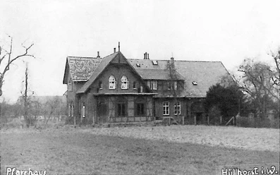 huellhorst-dorfplatz.jpg Ein historisches Fachwerkhaus steht inmitten einer Wiese, umgeben von Winterbäumen in Hüllhorst.