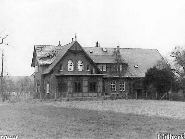 huellhorst-dorfplatz.jpg Ein historisches Fachwerkhaus steht inmitten einer Wiese, umgeben von Winterbäumen in Hüllhorst.