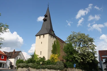 Andreaskirche Hüllhorst Die Andreaskirche Hüllhorst mit spitzem Kirchturm, umgeben von grünen Bäumen und blauem Himmel.