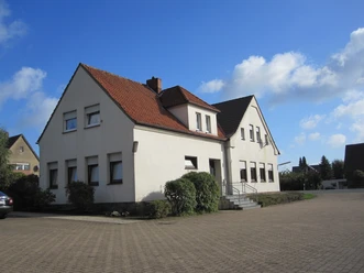 Dorfgemeinschaftshaus Oberbauerschaft mit weißer Fassade, rotem Dach und barrierefreiem Zugang.