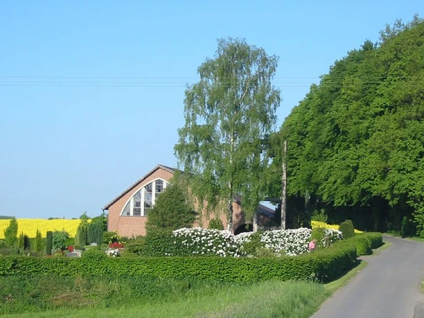 oberbauerschaft-friedhof-niedringhausen-02.jpg Ein friedlicher Friedhof befindet sich neben einer Landstraße, umgeben von üppigen Feldern und Wäldern.