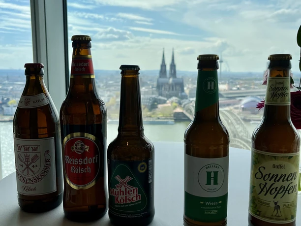 KölschTasting Kölsch Flaschen auf Stehtisch, im Hintergrund Kölner Dom
