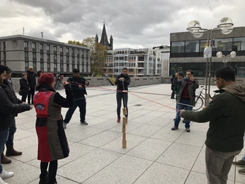 Team Köln Personen im Kreis mit Schnüren bei TeamaufgabePeople in a circle with strings for a team task