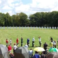 oberbauerschaft-alter-sportplatz-01.jpg Menschen beim Bogenschießen auf einer Wiese mit Zielscheiben, umgeben von Bäumen und Zuschauern.