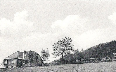 oberbauerschaft-koepperplatz-03.jpg Schwarzweißaufnahme eines kleinen Landhauses mit Bäumen, auf einer weitläufigen Wiese gelegen.