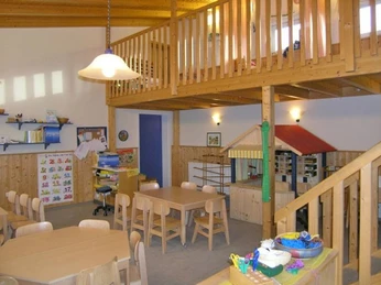 oberbauerschaft-familienzentrum-arche-02.jpg Heller Innenraum eines Familienzentrums mit Holzmöbeln, Spielzeug, Bastelmaterialien und Hochebene.