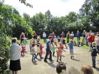 oberbauerschaft-familienzentrum-arche-03.jpg Kinder spielen fröhlich auf einem Hof, umgeben von Erwachsenen bei einer gemeinschaftlichen Veranstaltung.