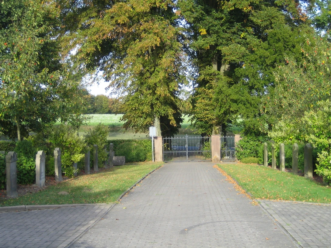 oberbauerschaft-friedhof-beendorf.JPG Eingang zu einem ländlichen Friedhof mit Tor und Bäumen, gesäumt von alten Grabsteinen.