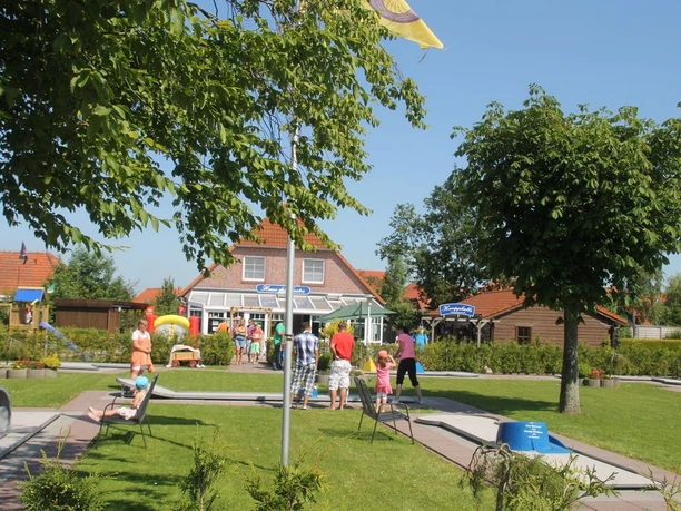 ankerplatz-werdum.jpg Blick auf den Minigolfplatz mit mehreren Bahnen sowie einem Haus im Hintergrund