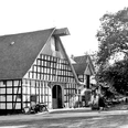 schnathorst-hof-niedermeier-01.jpg Historischer Fachwerkhof mit großen Scheunen und hohen Giebeldächern, umgeben von Bäumen.