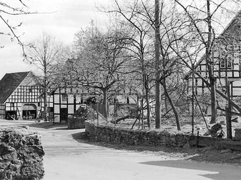 schnathorst-hof-niedermeier-02.jpg Fachwerkhäuser umgeben von kahlen Bäumen auf einem ländlichen Hof, Aufnahme in Schwarz-Weiß.