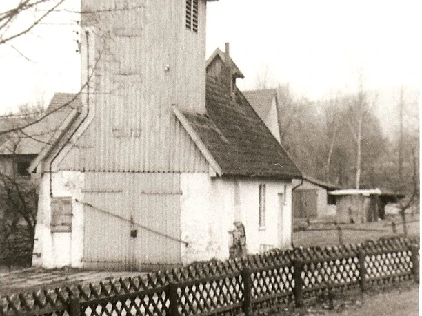 Altes Feuerwehrhaus mit hölzernem Schlauchturm, umgeben von Häusern und kahlen Bäumen im Hintergrund.