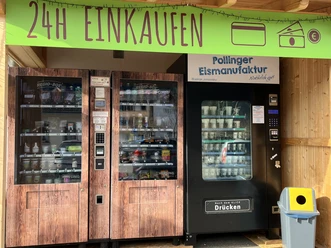 Lebensmittelautomat in FArchant 2-türiger Kühlschrank mit verschiedenen regionalen Lebensmitteln sowie ein Maschine für Softeis, darüber steht auf grünem Banner : 24 Stunden einkaufen zu bezahlen in bar und mit Karte