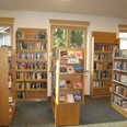 Gemeindebücherei Farchant Stehschränke mit verschiedenen Büchern, im Hintergrund Wandregale mit Büchern sowie 3 Fenster mit Rollos