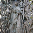 Bronzene Stele mit filigranem Blattwerk und Figuren, dargestellt als Frau mit Kind in sanfter Pose.