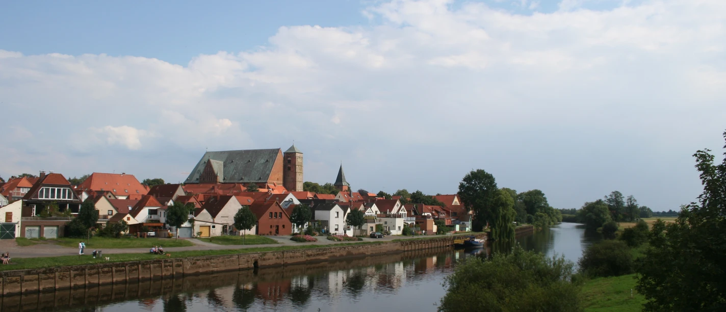 Eine malerische Altstadt mit Fachwerkhäusern und Kirche spiegelt sich im Fluss Verden wider.